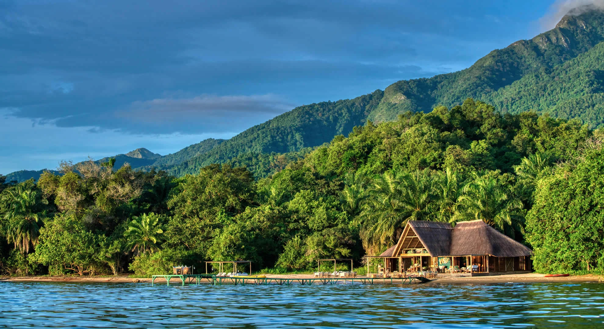 Mahale Mountains Accommodation surrounded by lush forest, mountains, and Lake Tanganyika in western Tanzania